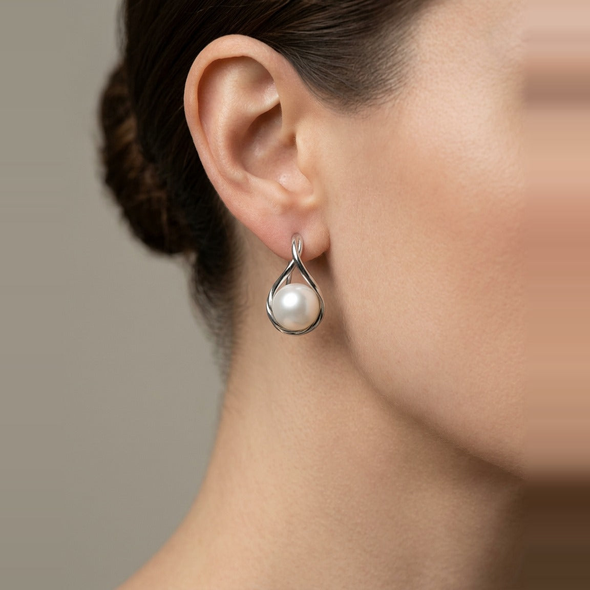 Polished silver metal setting holding white spherical pearl.