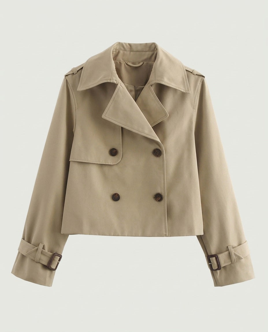 Front view of cropped trench jacket in camel with double-breasted buttons and buckled cuffs.
