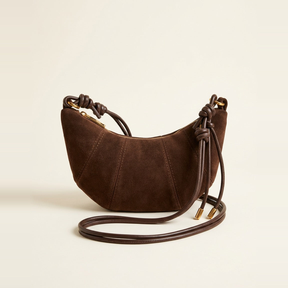 Chocolate croissant shoulder bag with soft nap finish and knotted strap details.