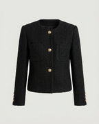 Front view of black collarless jacket with embossed metal buttons