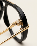Close-up of polished gold-tone metal temple and rim in black