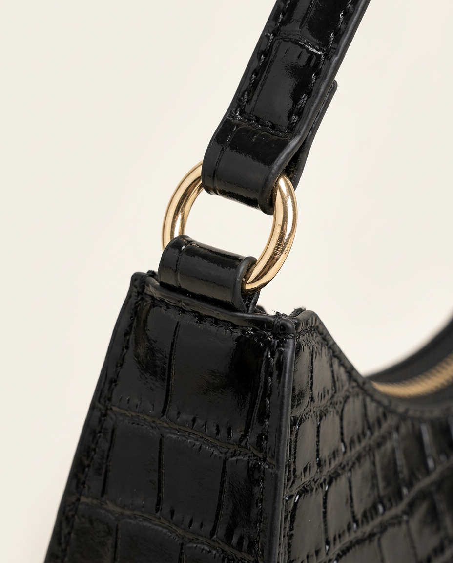 Close-up of the croc-embossed texture and metal zip pull in black.