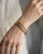 Thin bangles worn stacked on the wrist in Metallic