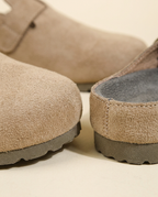 Macro view of the faux suede material and metal buckle on the Taupe mule.