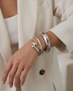 Close-up of the wide, open cuff bracelet in Silver worn on the arm.