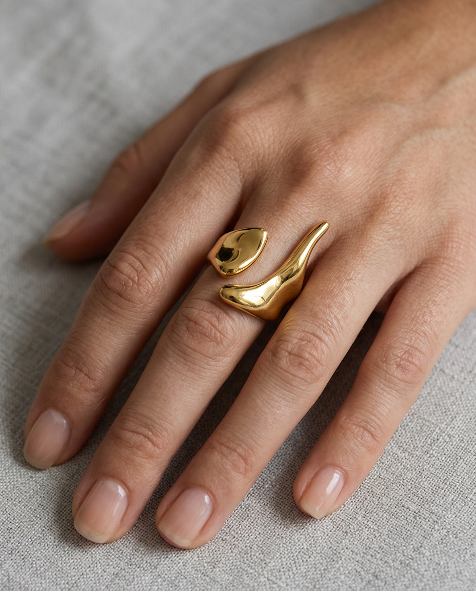 Asymmetrical silhouette of the open ring held close to the finger in Gold.