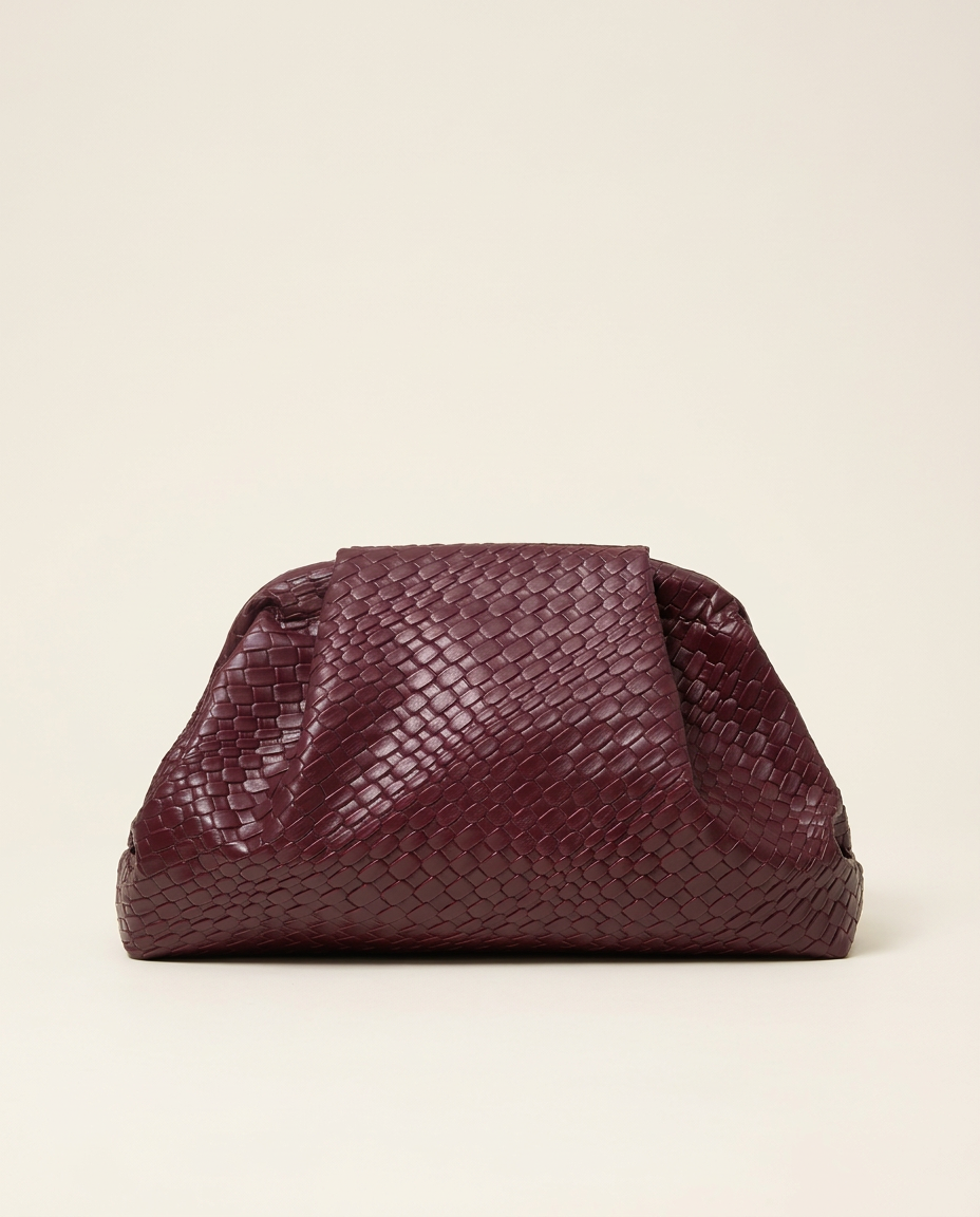 Woven pouch clutch in burgundy sitting on a white plinth