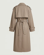 Long taupe trench coat from the back, belted at the waist, with back storm flap