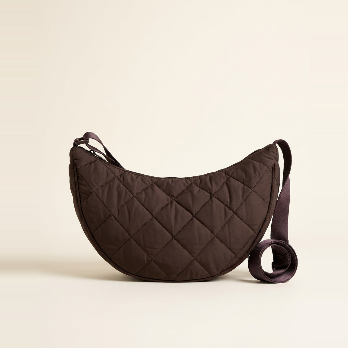 Woman wearing the Chocolate Quilted Crescent Shoulder Bag across her body.