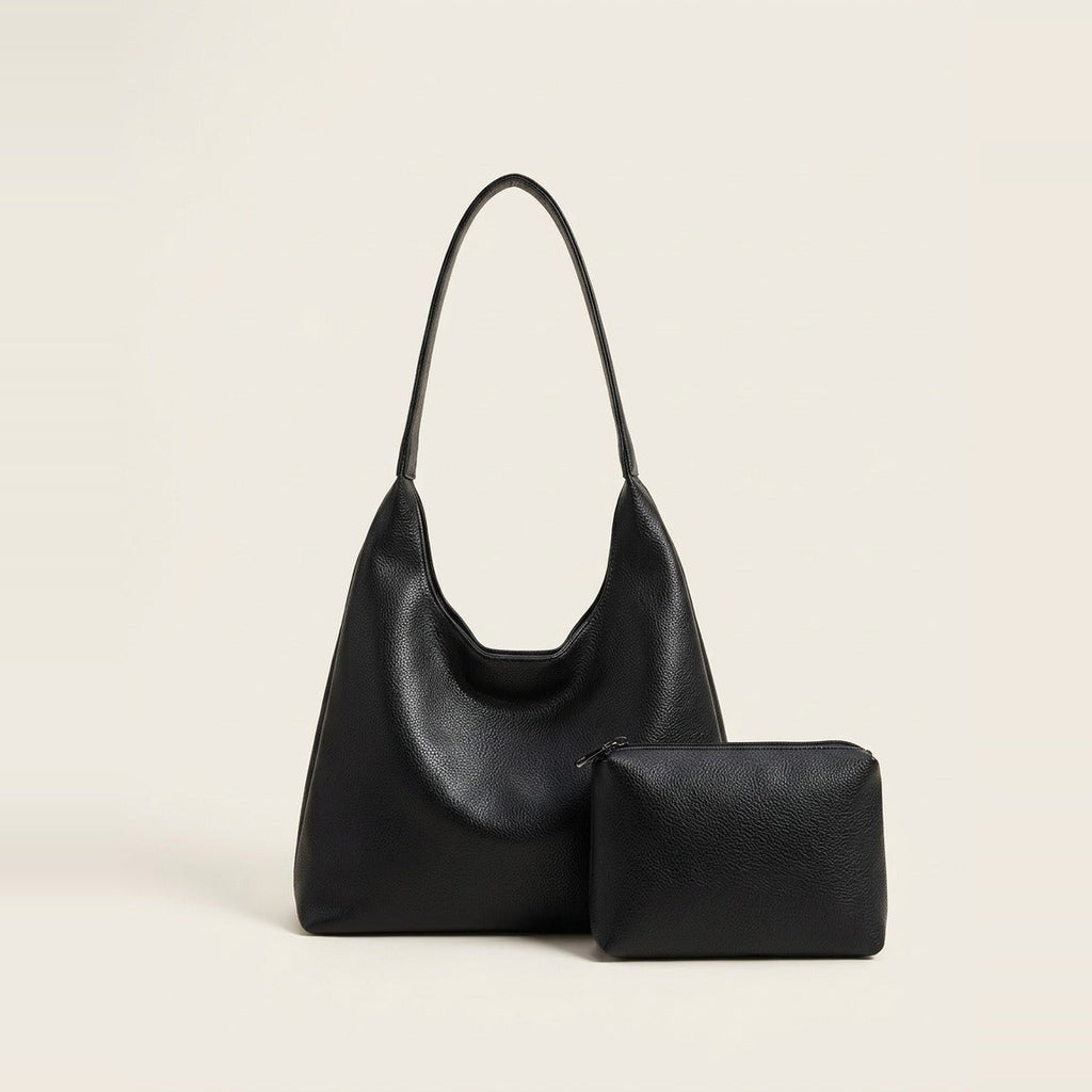 Slouchy hobo shoulder bag and matching pouch in black resting by a window