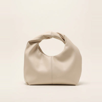 Twisted handle hobo bag in cream sitting on a display surface