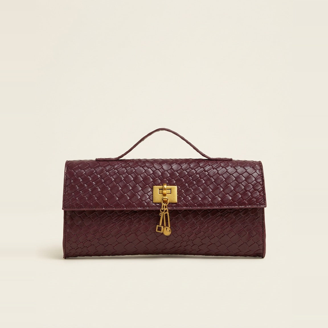 Rectangular woven top handle clutch in burgundy against a white background.